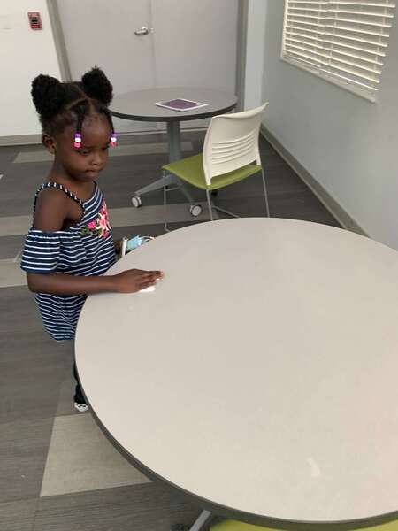 Little girl wiping down a table
