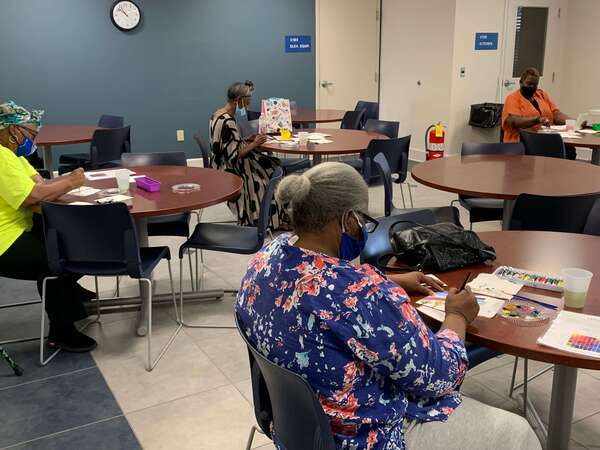 individuals sitting down painting with watercolor