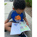 boy sitting on sidewalk reading a book