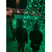 three children standing next to green christmas lights