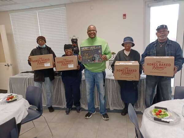 group of people holding boxes of ham