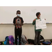 two boys standing next to one another holding a sign