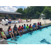 group of children sitting together lined up in front of a pool